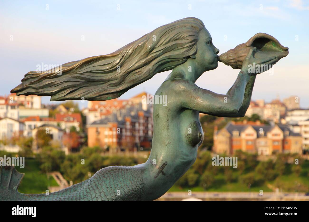 Bronze mermaid sculpture with long flowing hair blowing into a conch shell Museum of man and the sea Magdalena Peninsular Santander Cantabria Spain Stock Photo