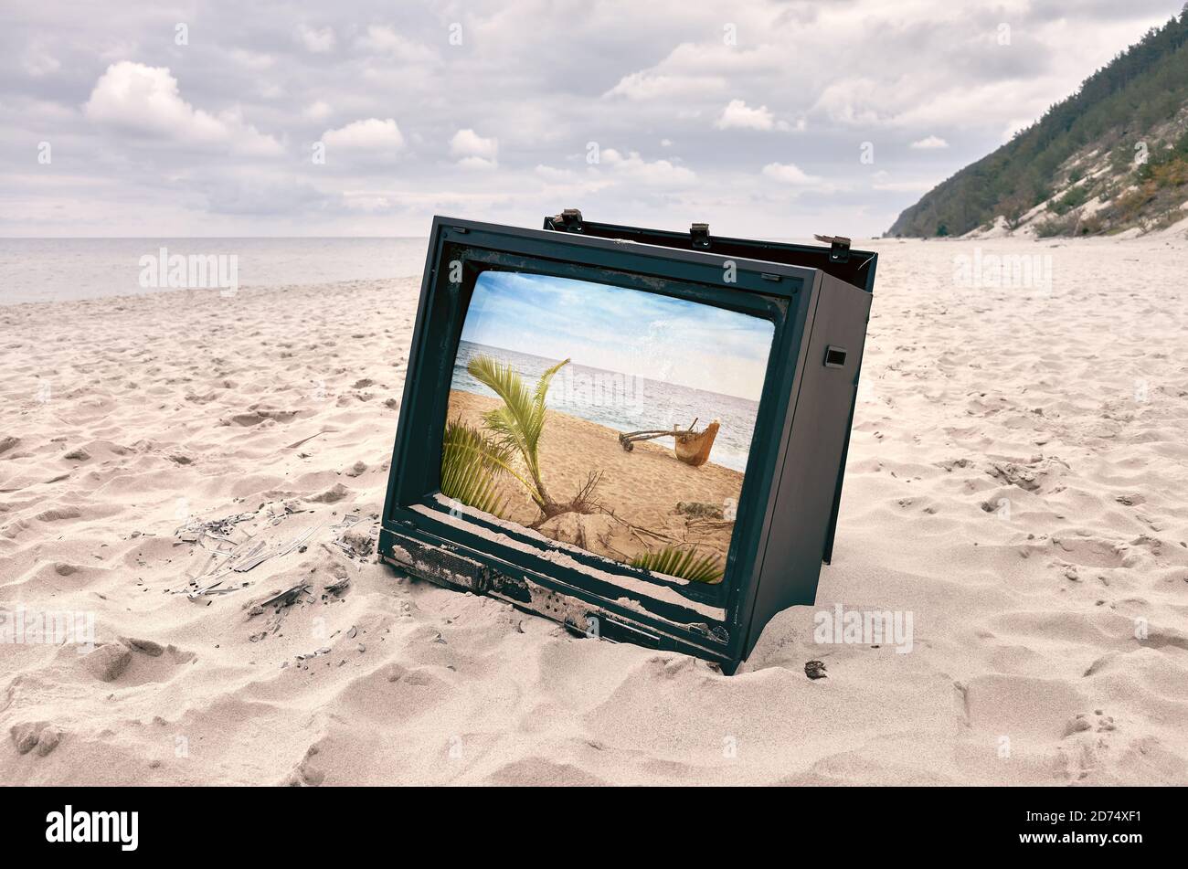 Old broken TV set on a beach with tropical view on display, color toning applied. Stock Photo