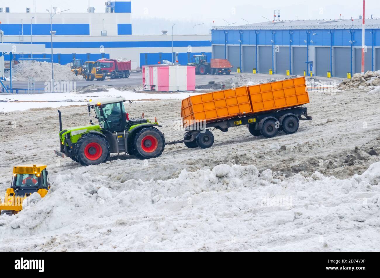 A powerful tractor with a trailer transports snow from city streets to