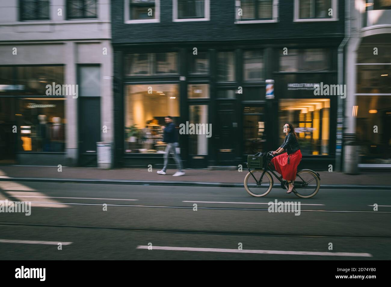 Young woman in a red dress cycling the Amsterdam streets. Stock Photo