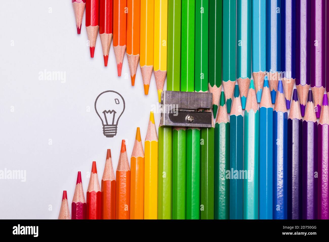 Colour pencils organized in the shape of a zipper opening up to a light bulb as a symbol of creativity Stock Photo