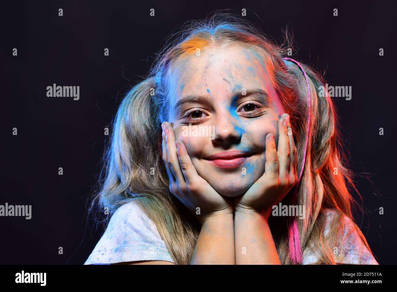 Kid with ponytails makes art. Girl with smiling face on black