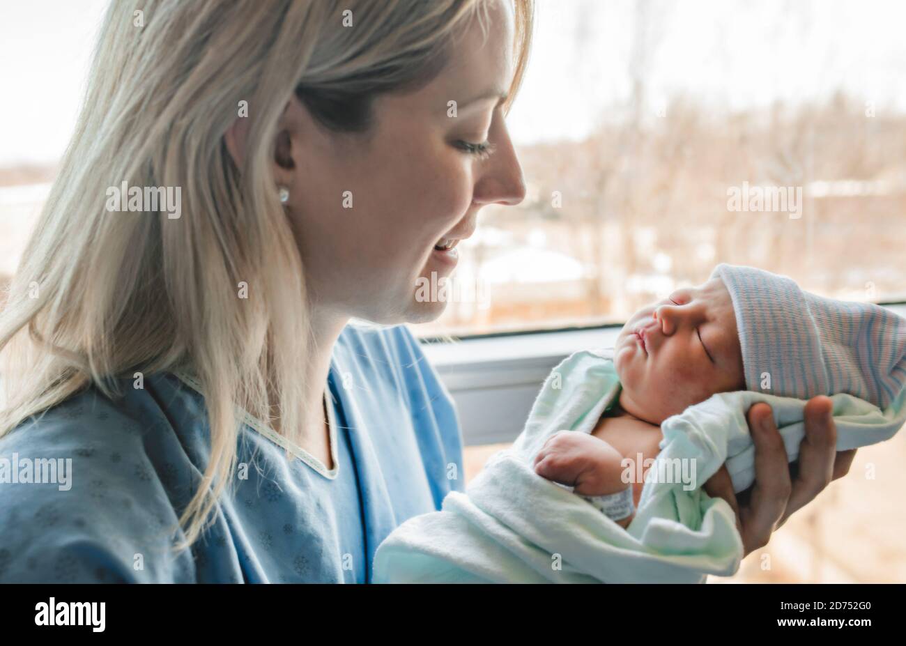 A Mother with her newborn baby at the hospital in front of a window