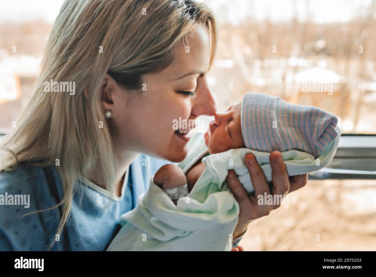 A Mother with her newborn baby at the hospital in front of a window