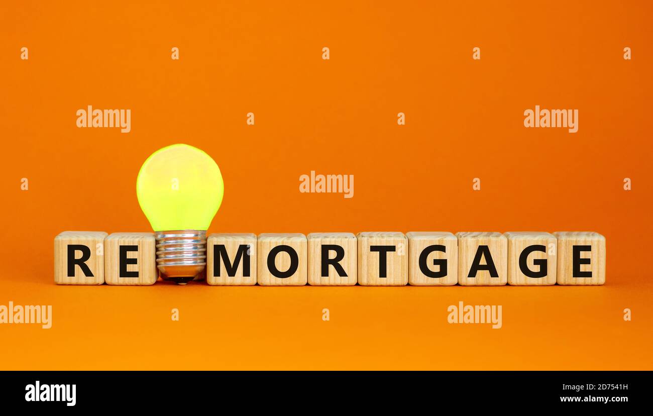 Wooden cubes with word 'remortgage'. Yellow light bulb. Beautiful orange background. Business concept. Copy space. Stock Photo