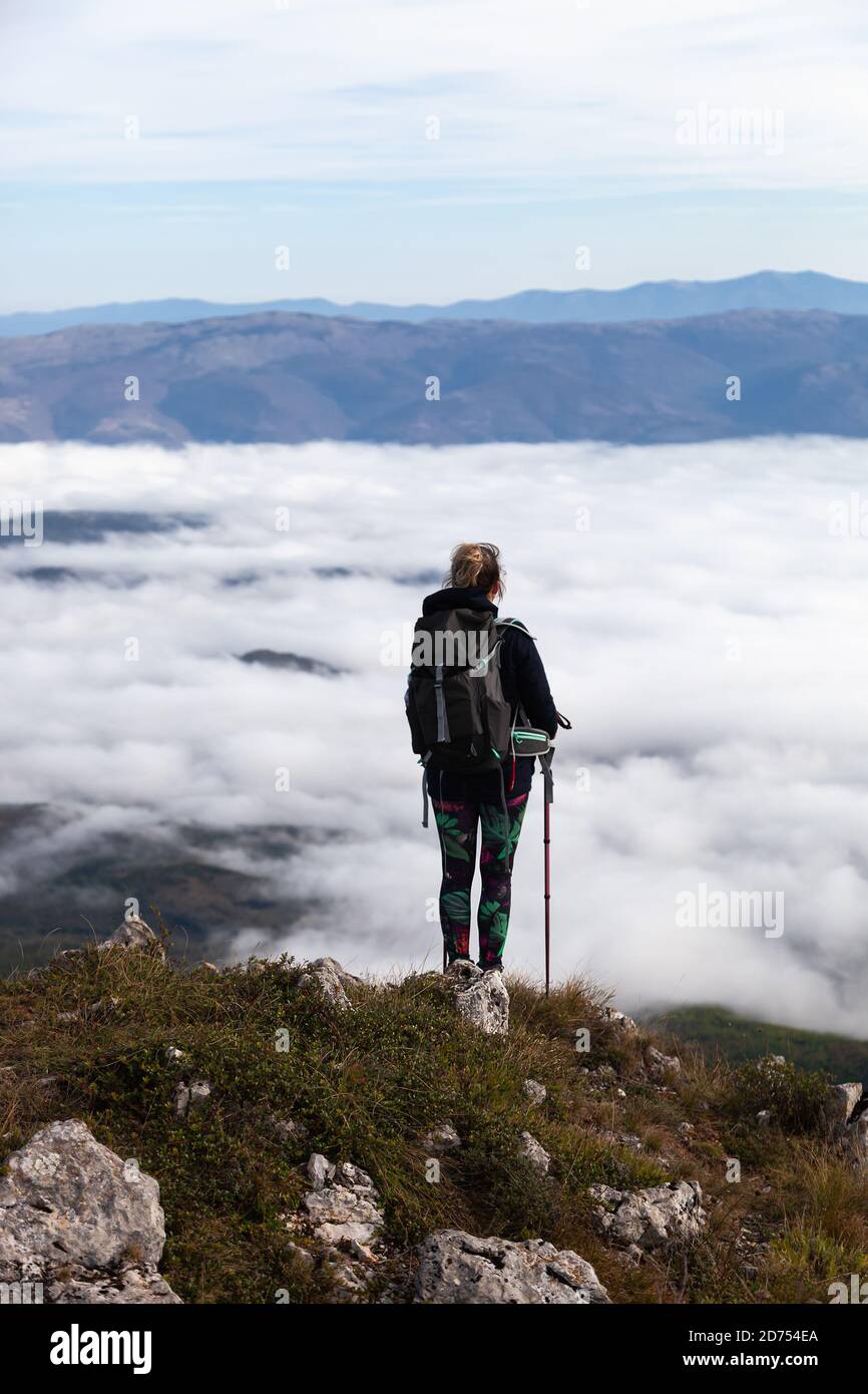 Girl, mountain hiker with walking sticks above clouds from Suva planina (Dry mounain) Stock Photo