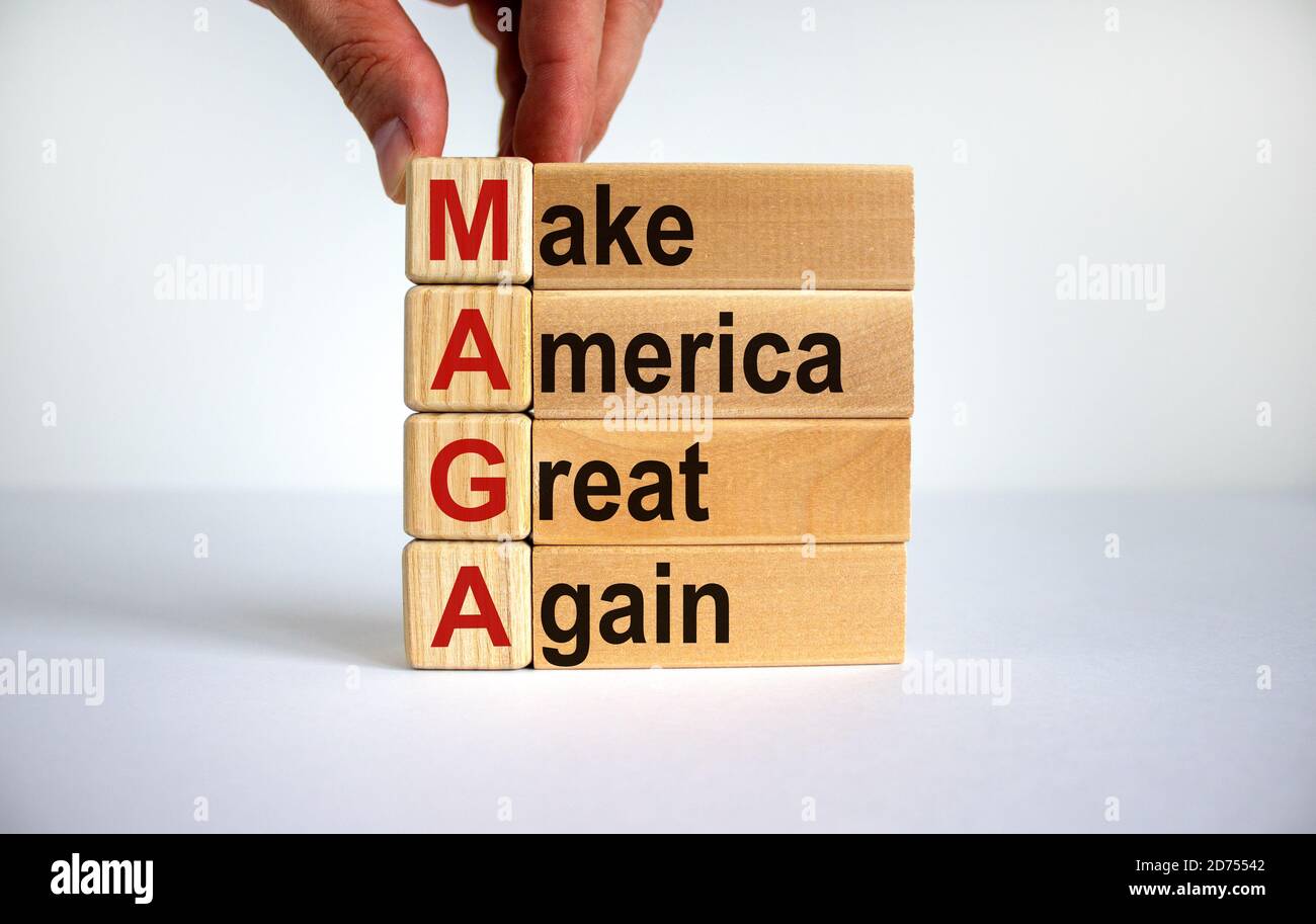 Concept words 'MAGA, Make America Great Again' on wooden cubes and blocks on a beautiful white background. Male hand. Copy space. Stock Photo