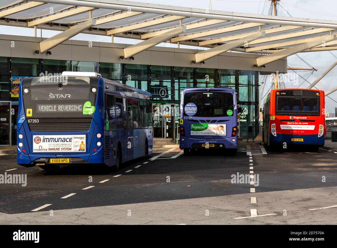 A single decker bus entering a bus terminal alongside two buses parked ...