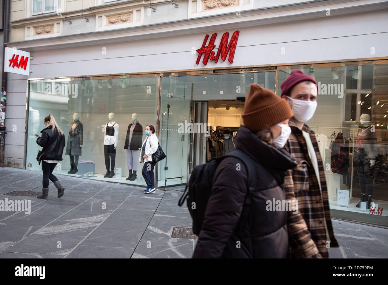 People wearing face masks walk past the Swedish multinational clothing  retail company H&M store in Ljubljana after Slovenia redeclared an  epidemic.As daily new covid-19 cases passed twenty percent of all tested  Slovenia