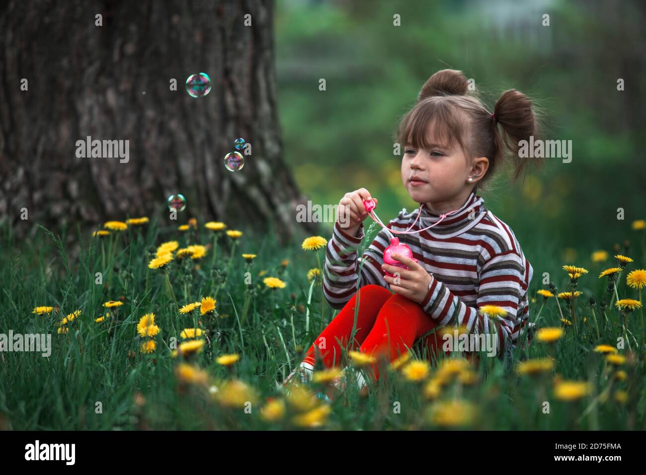 Little cute girl blowing soap bubbles in the park Stock Photo - Alamy