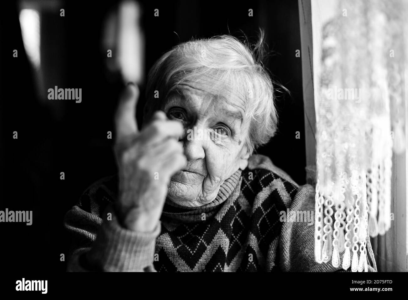 An elderly woman threatens with a finger looking at the camera. Black and white photography. Stock Photo