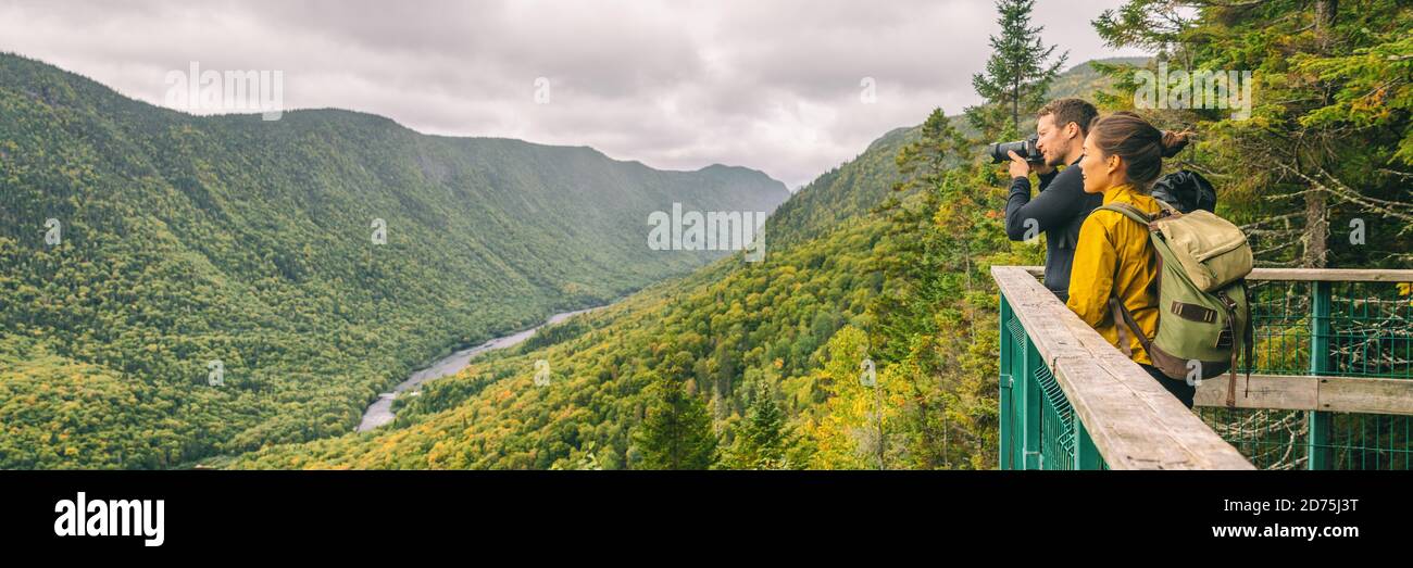Travel couple hikers tourists taking photo with camera at view of mountain landscape in Autumn forest Parc de la Jacques Cartier, Quebec, Canada Stock Photo