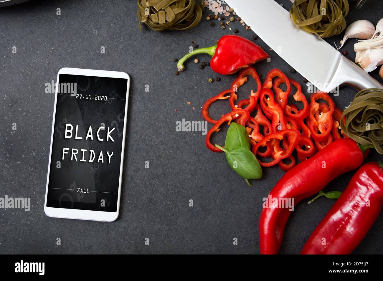Modern smartphone with black friday banner on the screen lies on countertop with spicy vegetables Stock Photo
