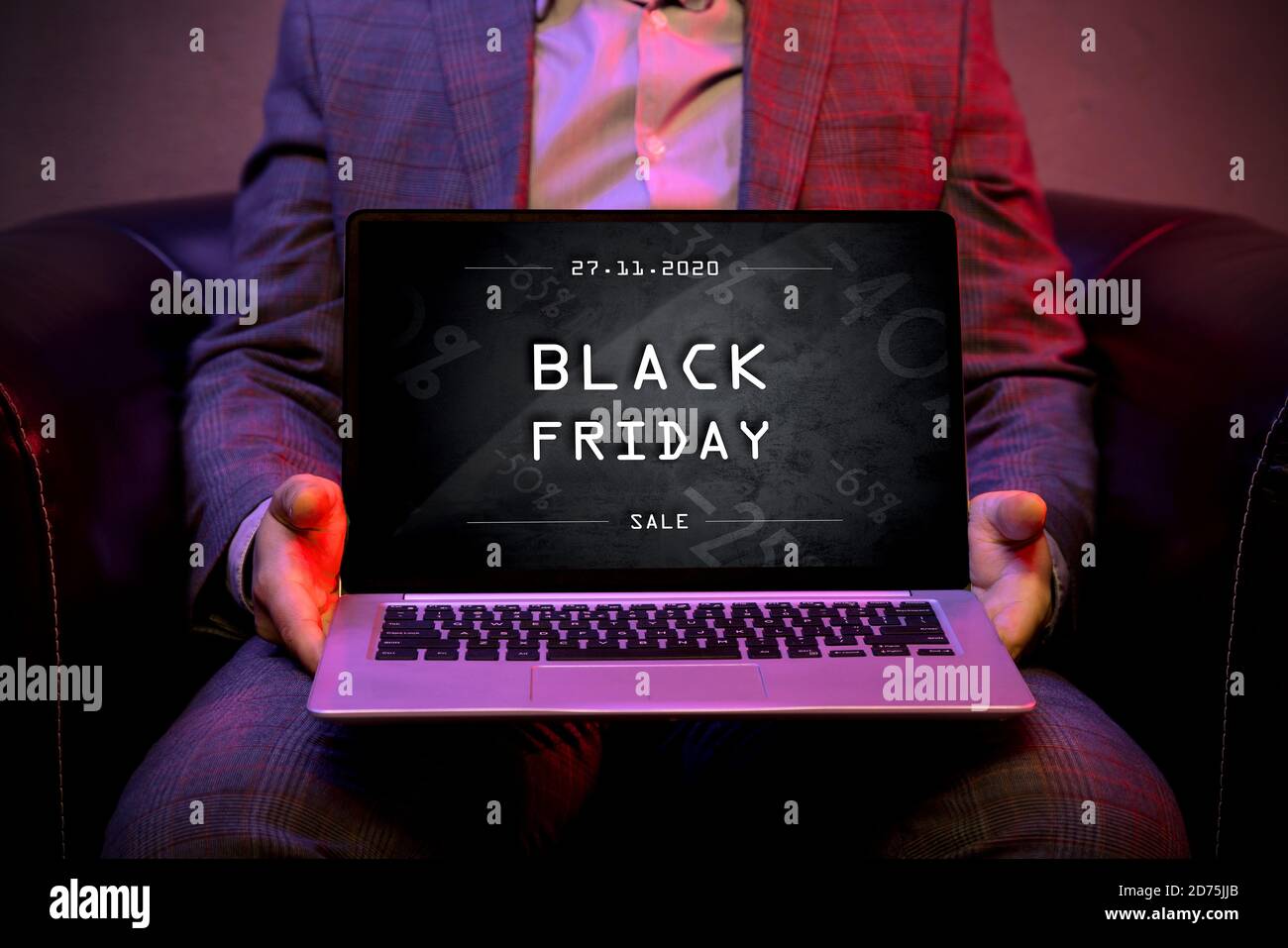 Black friday banner on the display of a modern laptop that is holds by an elegant man. Stock Photo