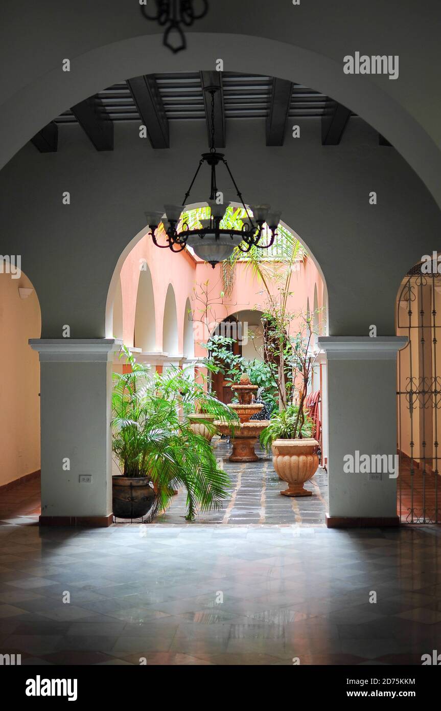 Old San Juan interior patio with an arch at the entrance and plants surrounding the fountain