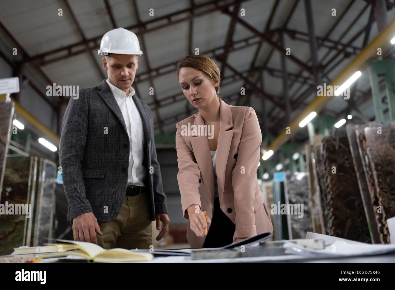 From below of professional business workers discussing blueprint while picking materials on stone manufacture Stock Photo