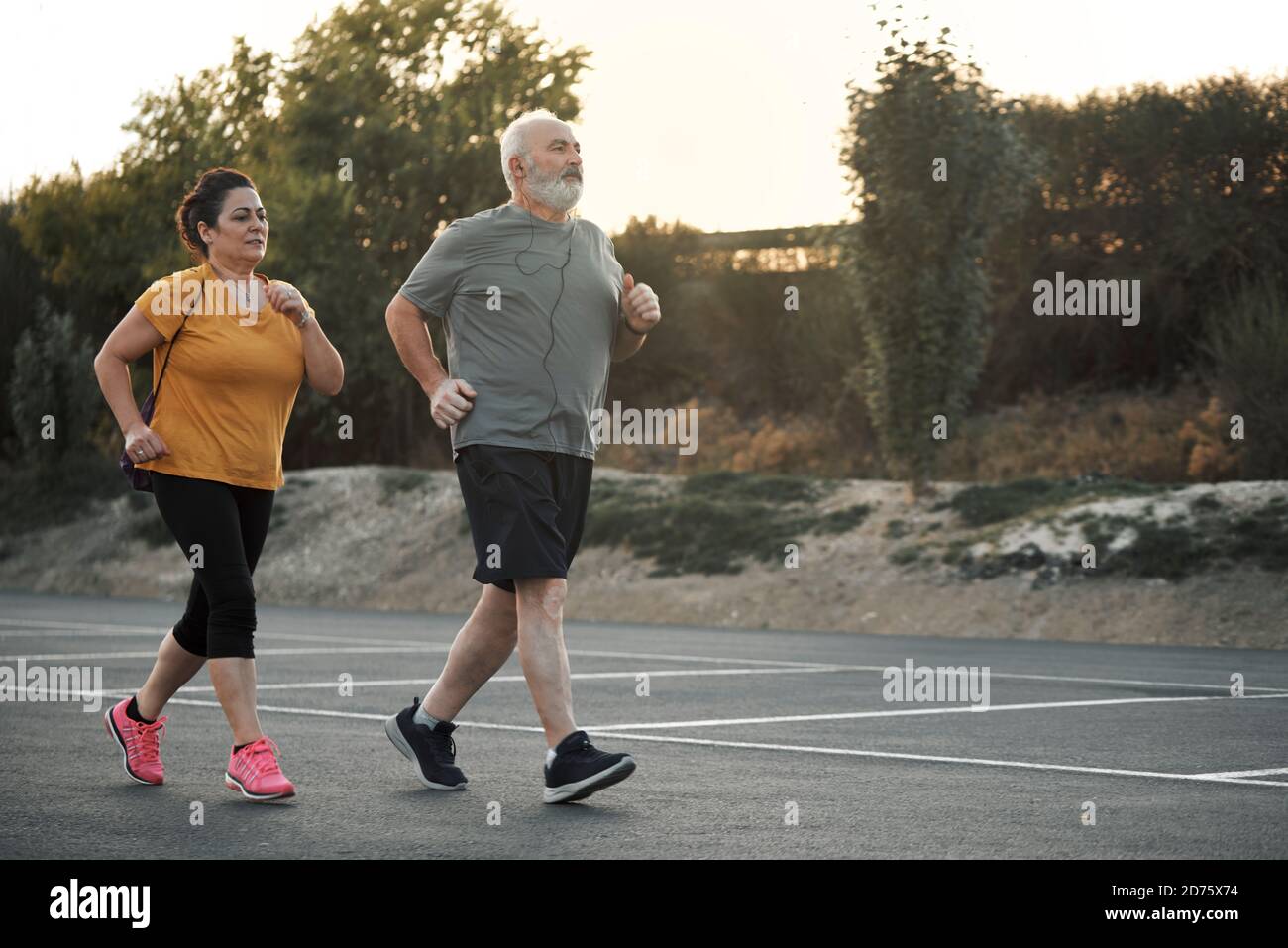 A woman and an elderly man are jogging in the street Stock Photo