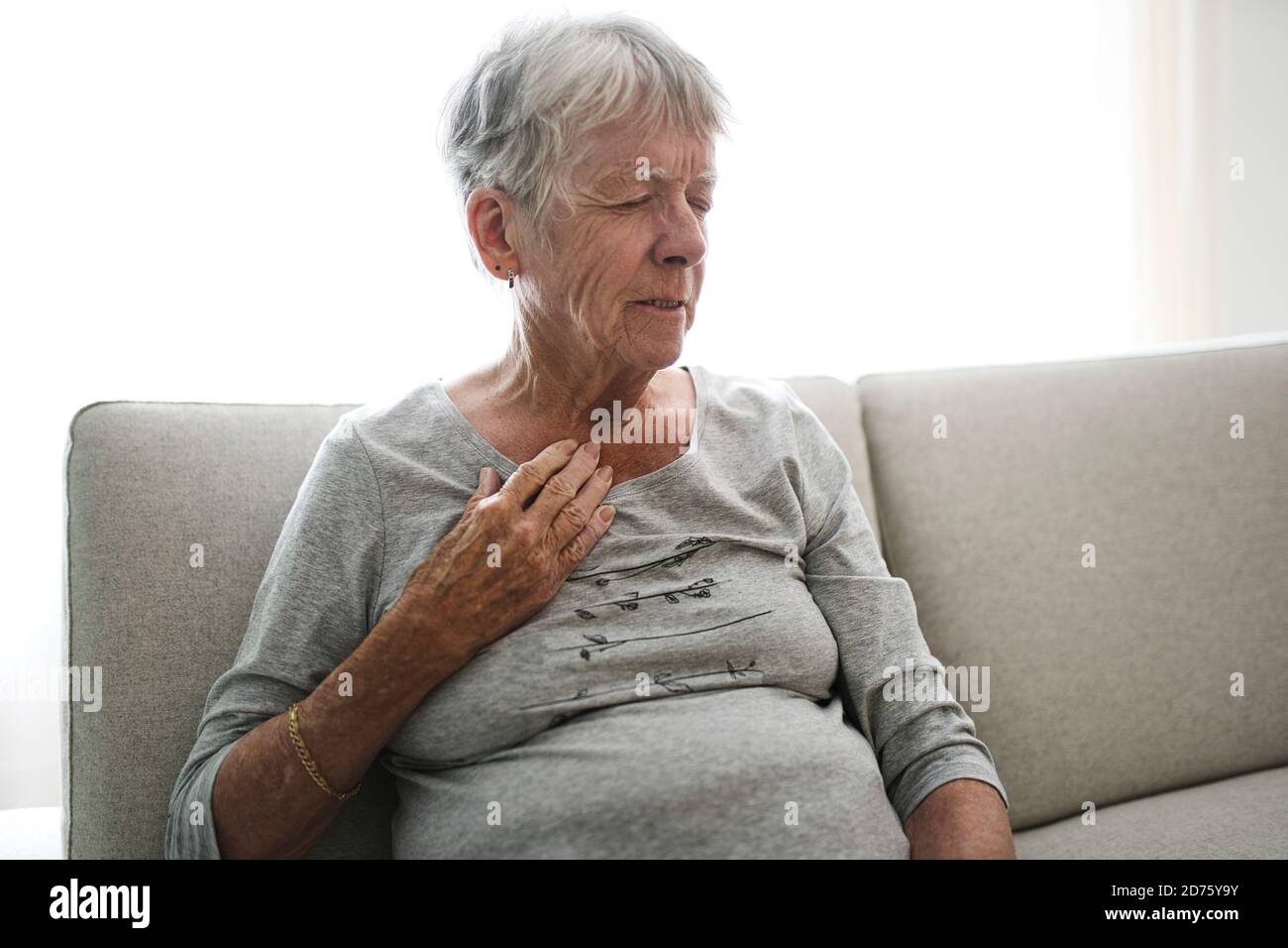 Upset stressed mature middle aged woman feeling pain ache touching chest having heart attack Stock Photo