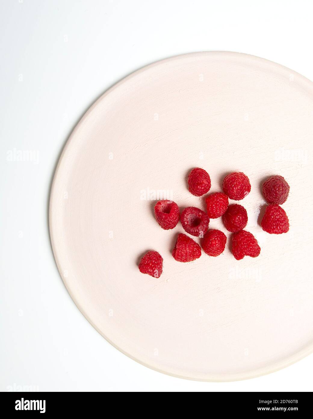 High Angle View of Raspberries on Cropped White Plate Stock Photo