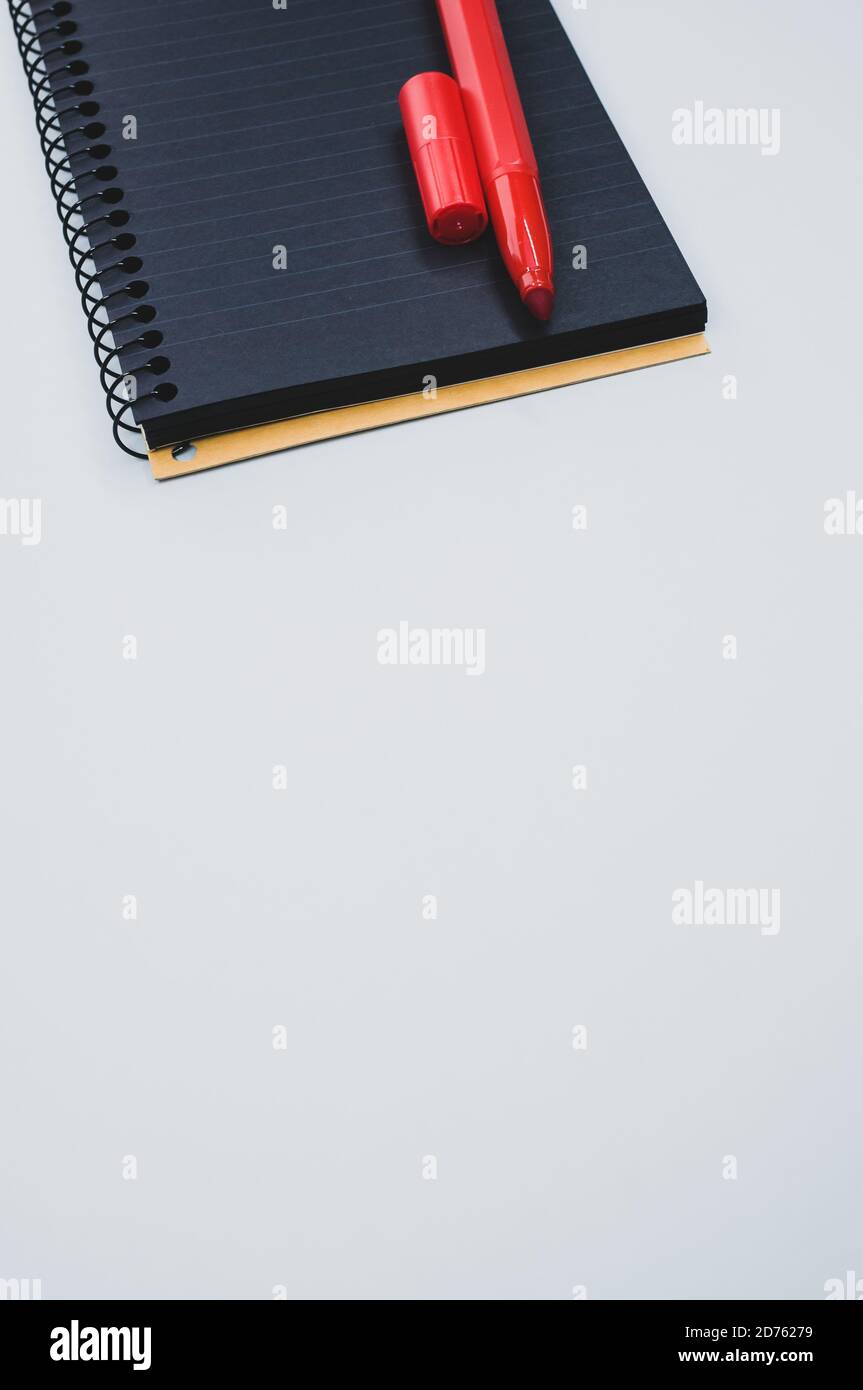 Vertical shot of a notebook and a marker on a blue surface Stock Photo