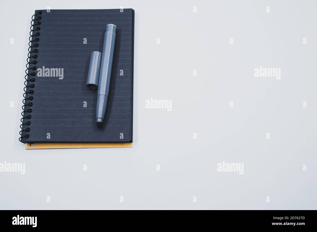 High angle shot of a black notebook and a marker on a blue surface Stock Photo