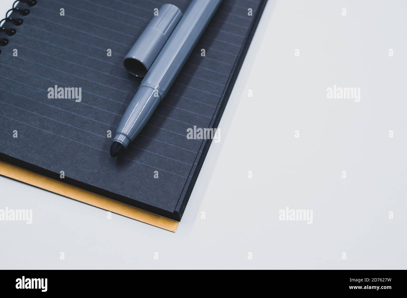 High angle shot of a black notebook and a marker on a blue surface Stock Photo