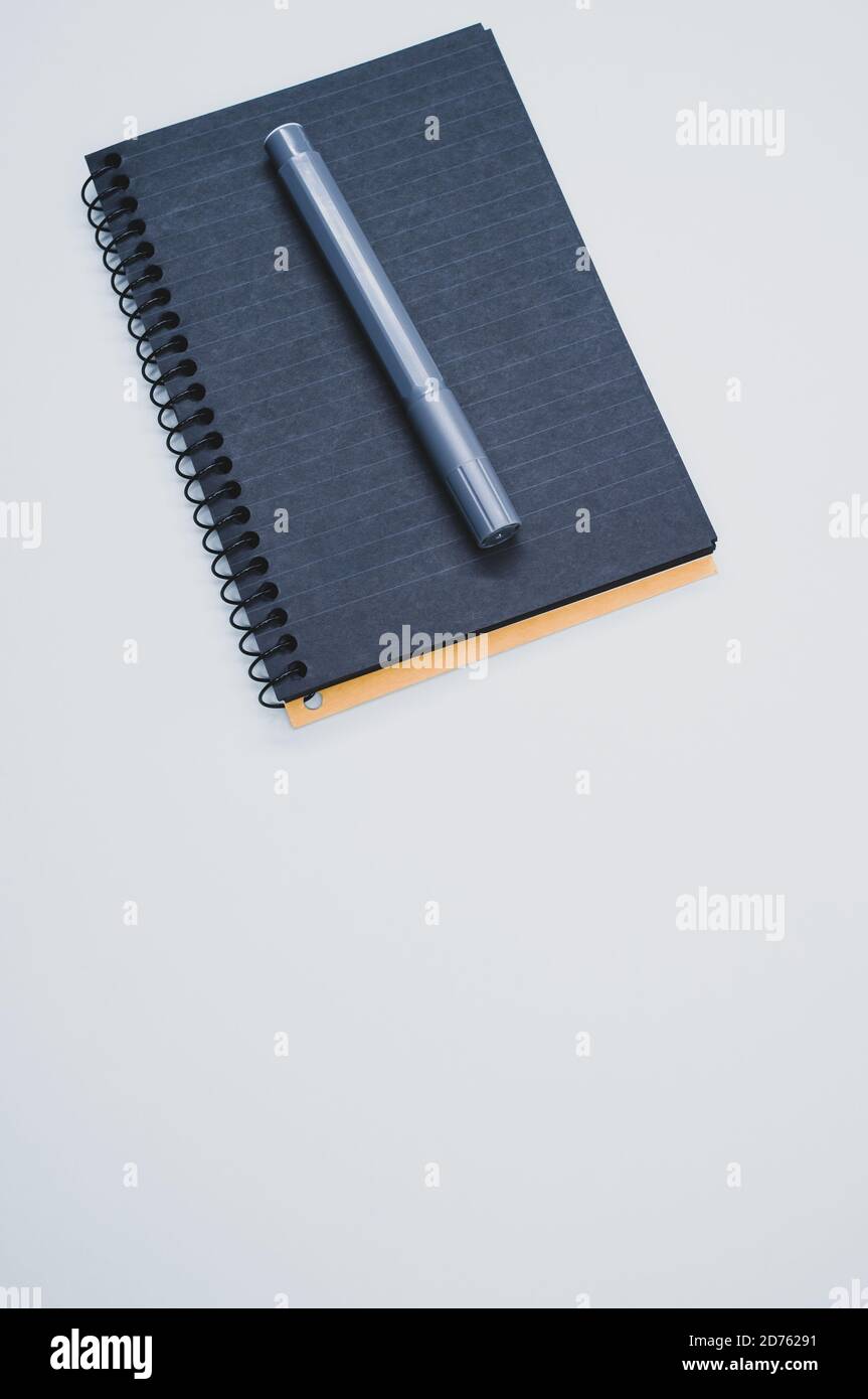 Vertical shot of a notebook and a marker on a blue surface Stock Photo