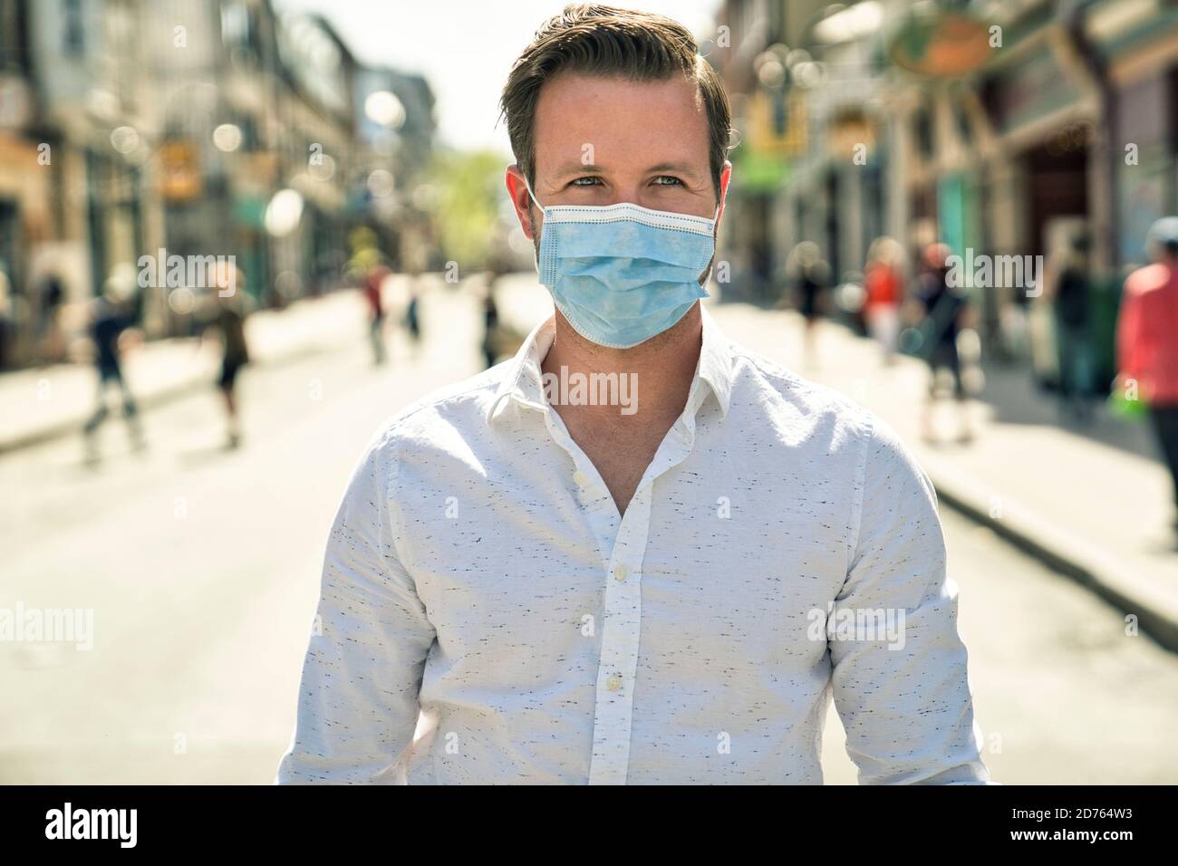 Portrait of brunette man in a medical surgical mask in the summer city. Coronavirus, illness, infection, quarantine. Stock Photo