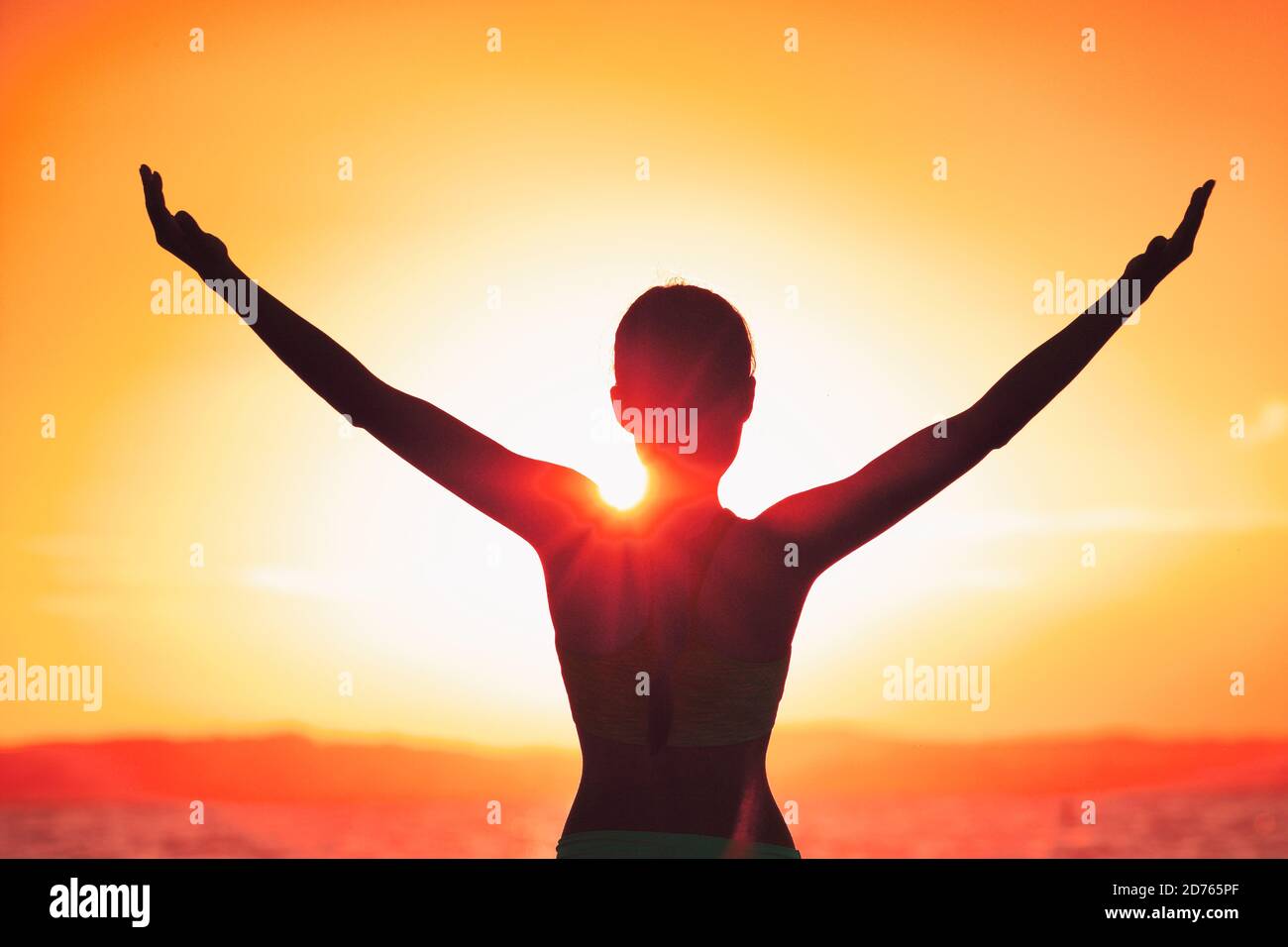 Carefree happiness woman with open arms silhouette in sunset. Success freedom happy life concept in sunrise. Morning yoga girl practicing sun Stock Photo