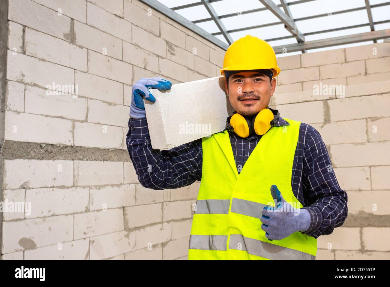 Worker reassure holds autoclaved aerated bricks in construction site, Concept proposes to use autoclaved aerated bricks in construction of houses. Stock Photo