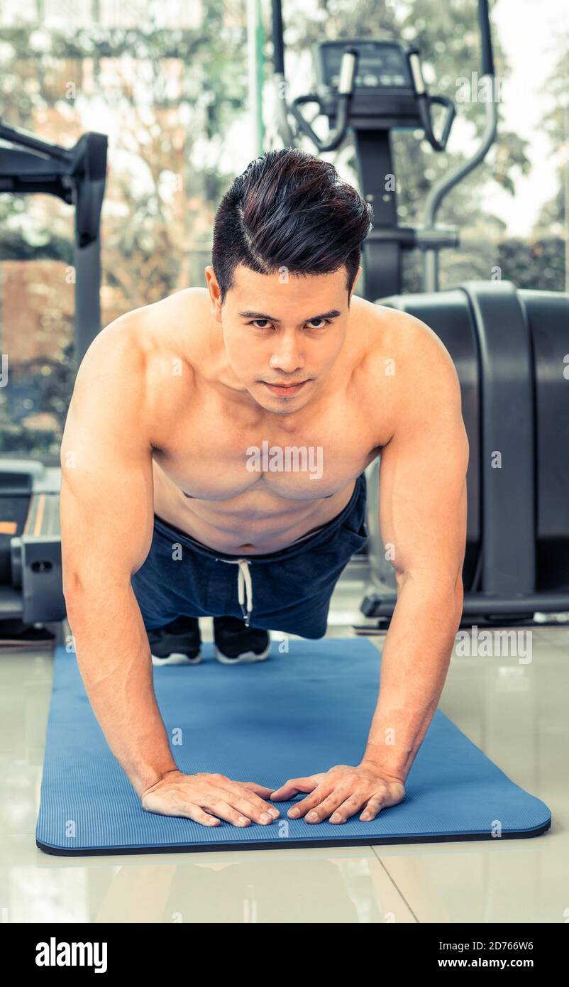 Young man bodybuilder doing push up in fitness center. Healthy