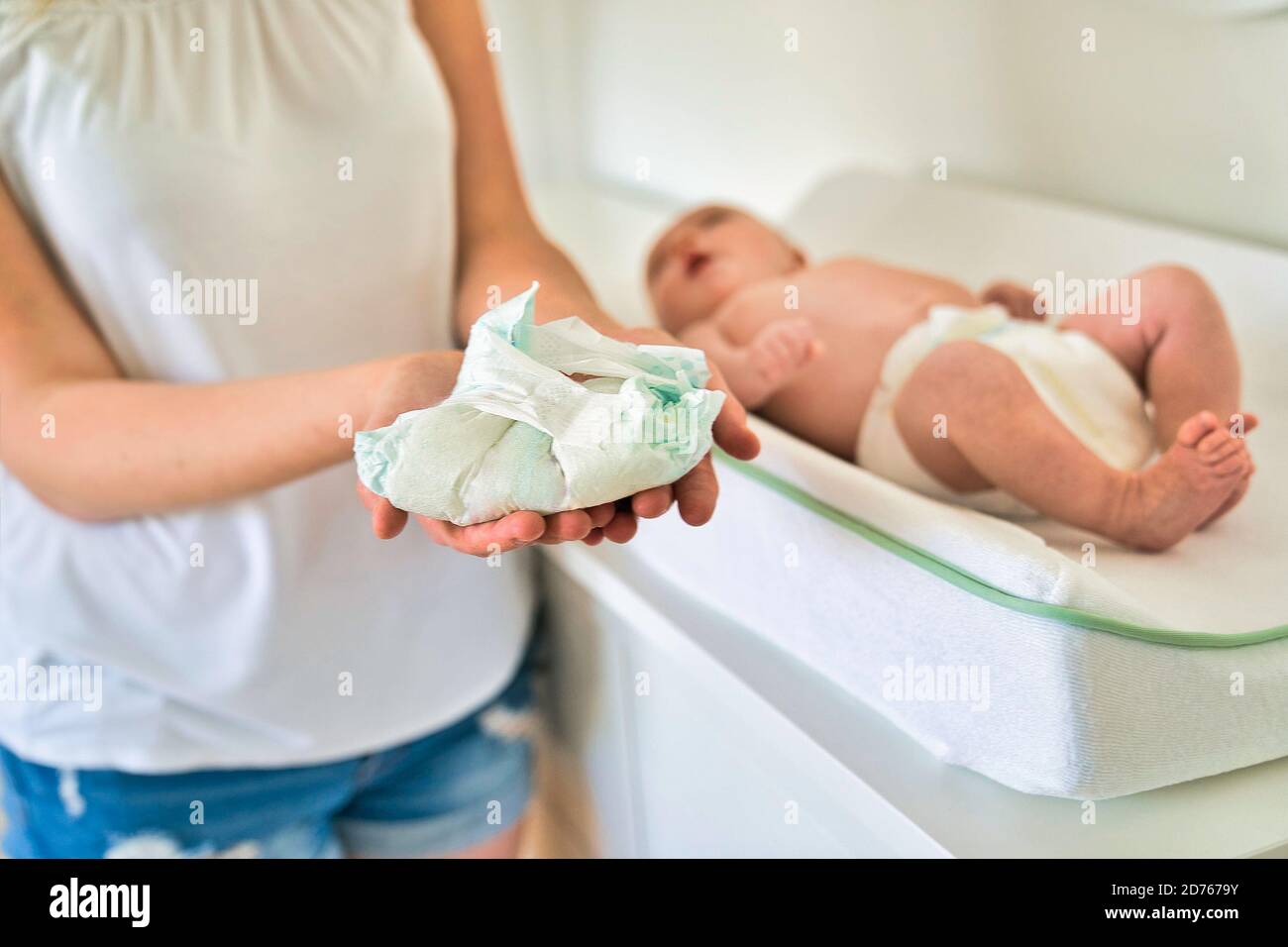 A mother Changing Baby's Diaper In nursery holding diaper Stock Photo