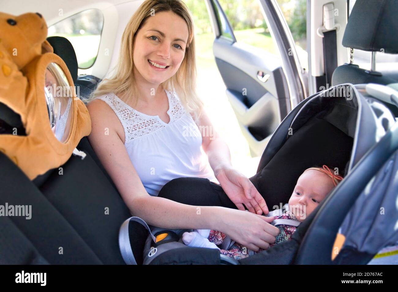 A Young mother and child in car. Baby seat on chair. Safety driving