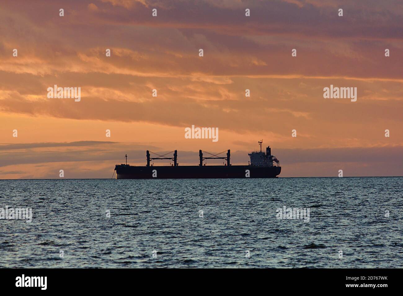 Freight ship silhouette at sunset, horizon view, open ocean. Vancouver, British Columbia, Canada Stock Photo