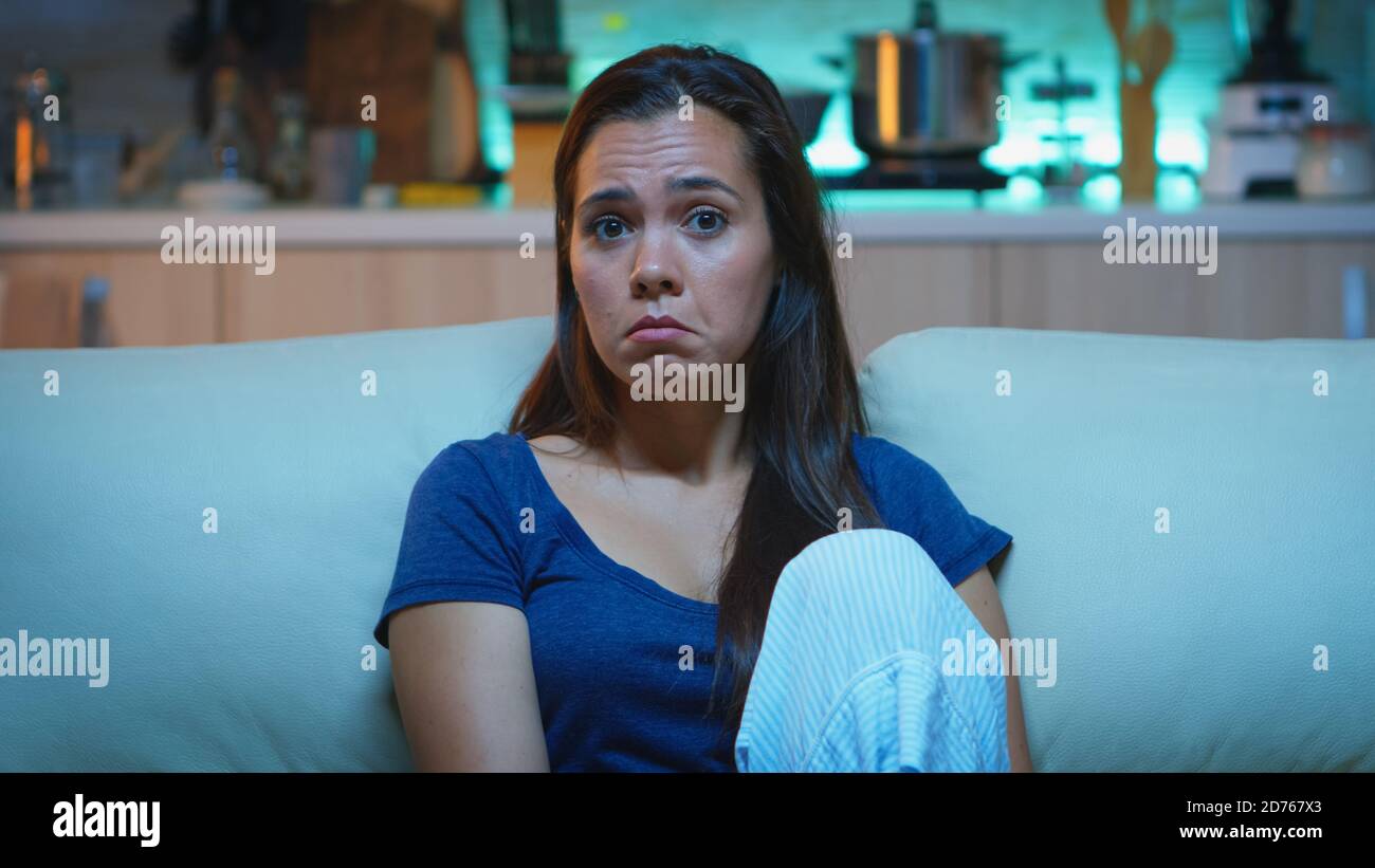 Focused young woman paying attention to film with a shocked concentrated and amazed facial expression. Emotionally awestruck and wide-eyed lady reacting to an impressive and astonishing moment on tv Stock Photo