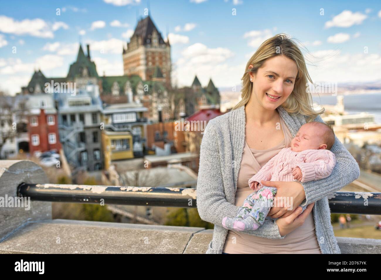 blonde women with baby at the blurred Frontenac Castle in the background, Quebec, Canada Stock Photo