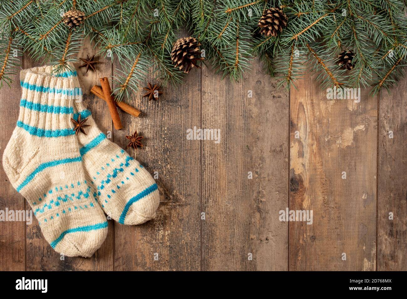 Vintage Christmas background. Wooden rustic background with fir branches, cones, cinnamon sticks, anise, wool socks. Copy space. top view Stock Photo