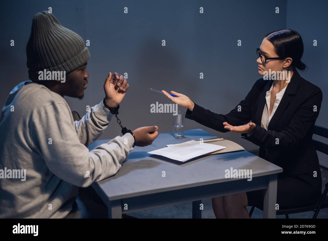 A black guy listens to his rights from a civil lawyer at a table in a visiting room in a state prison Stock Photo