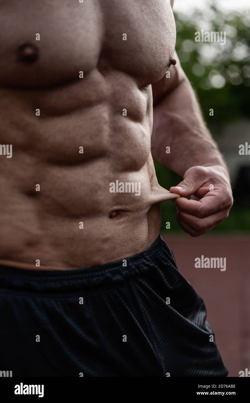 low fat diet and training concept of strong young man holding his thin skin  on abdominal muscle outdoors workout Stock Photo - Alamy