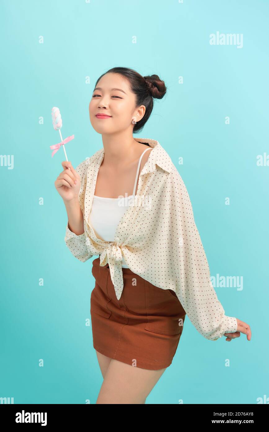 Teenager asian girl holding a lollipop over isolated blue background Stock Photo