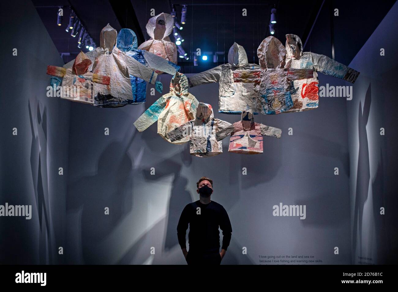 A staff member looks at woven Inuit clothing that form an artwork ...