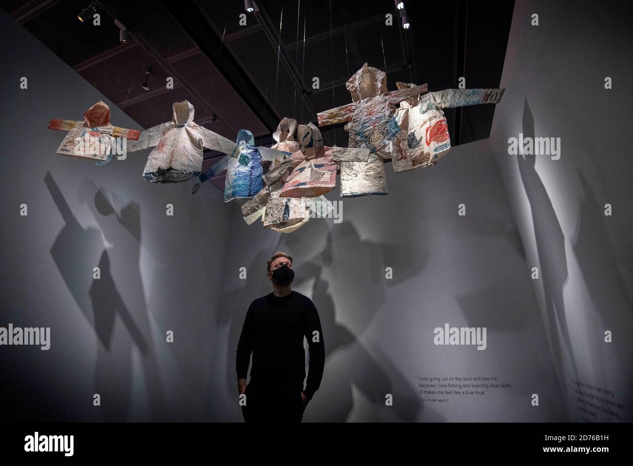 A staff member looks at woven Inuit clothing that form an artwork ...