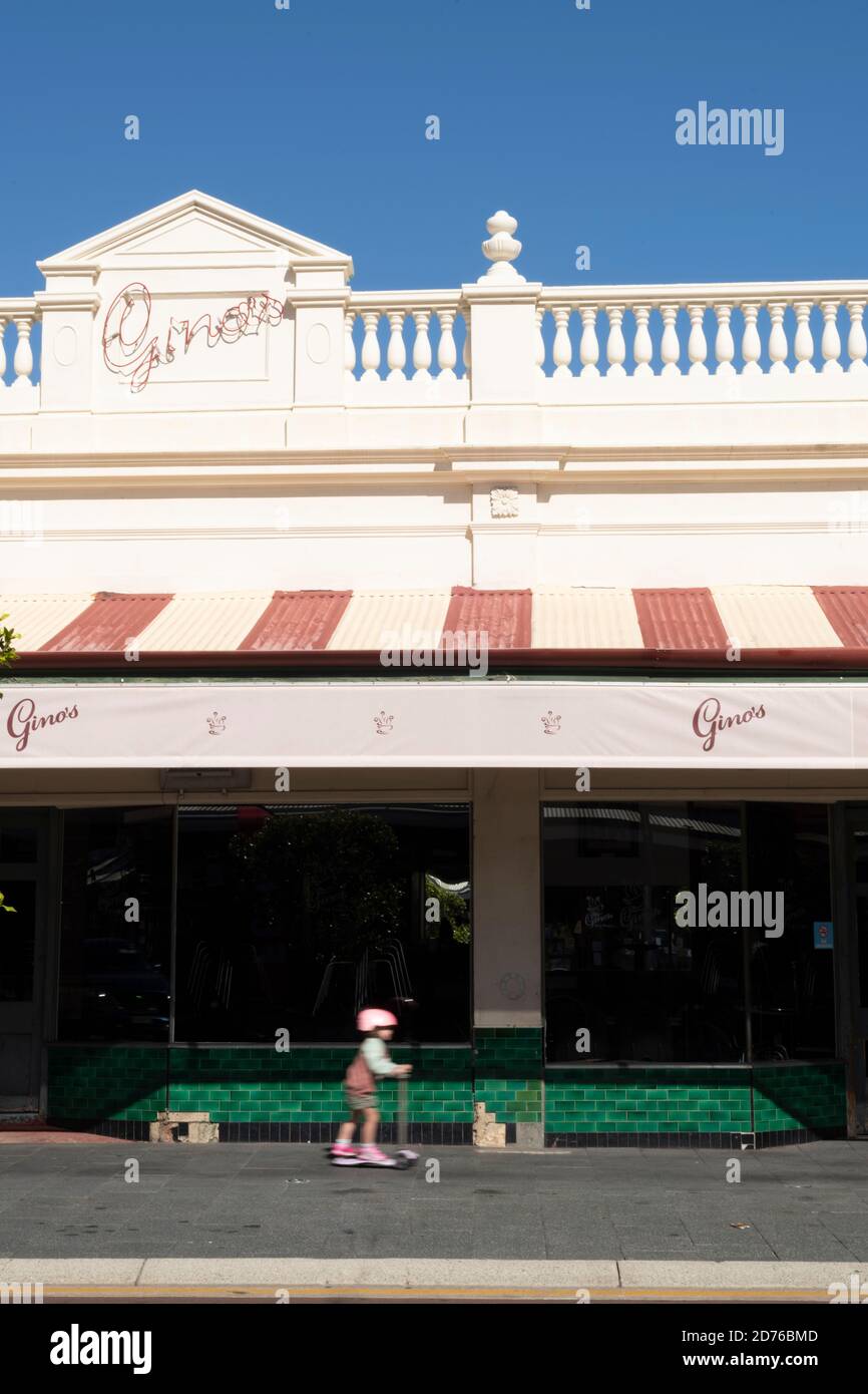 Child rides scooter past Gino's during COVID-19.  Normally very busy, the cafe is closed. Stock Photo