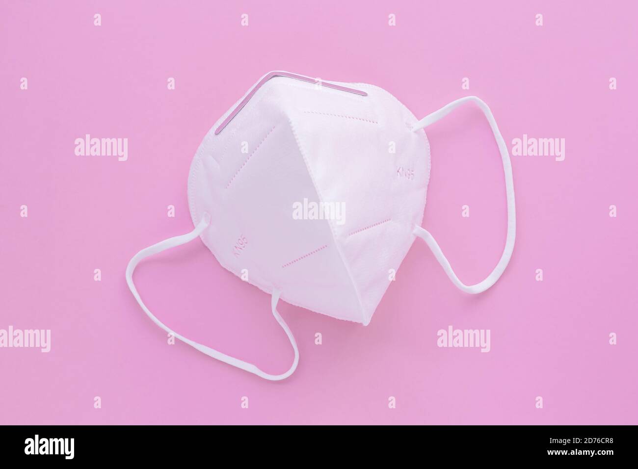 Protective medical face filter mask to cover the mouth and nose. White surgical KN95 respirator, pink background. Covid-19 prevention, protection conc Stock Photo