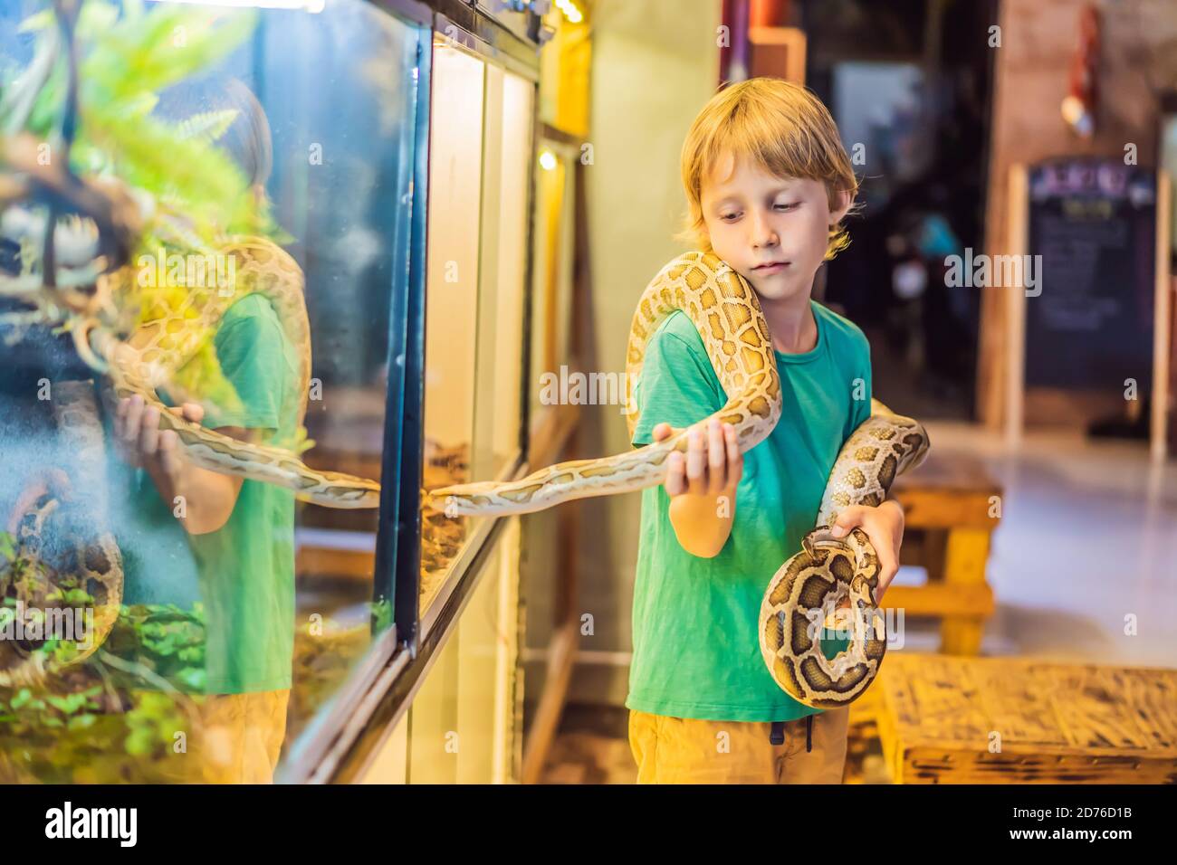 Smiling boy holding python in his hands Stock Photo