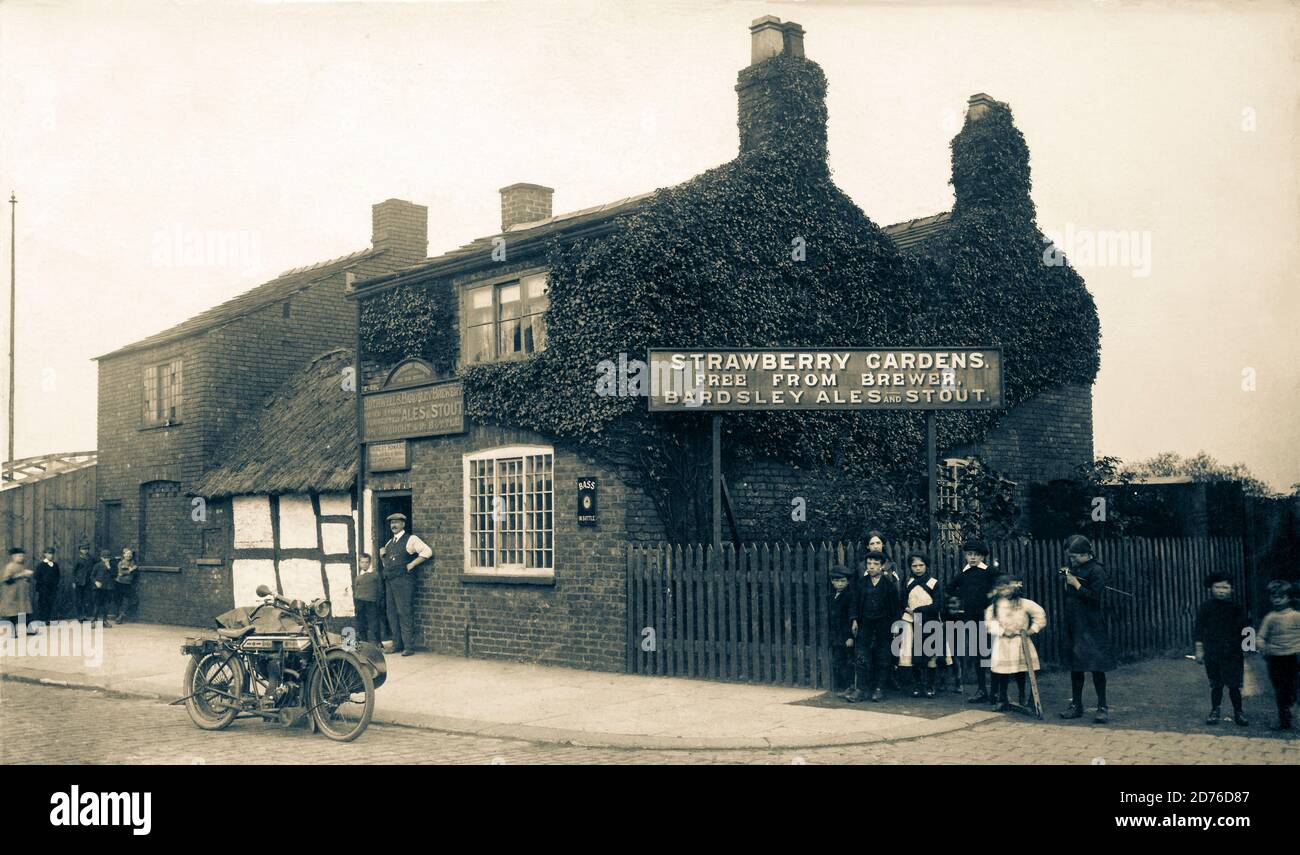 Very rare image of the Strawberry Gardens public house, Droylsden Manchester. Includes Early ridge motorcycle, could be a 'Multigear' first manufactured in 1912. Groups of children and the Pub Landlord at the door. Really pleasing image of the time. Stock Photo