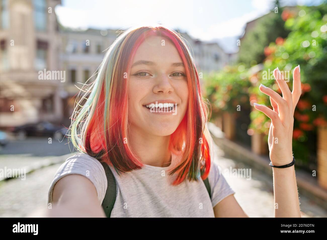 Fashionable teenage girl looks at webcam and talks on city street Stock Photo