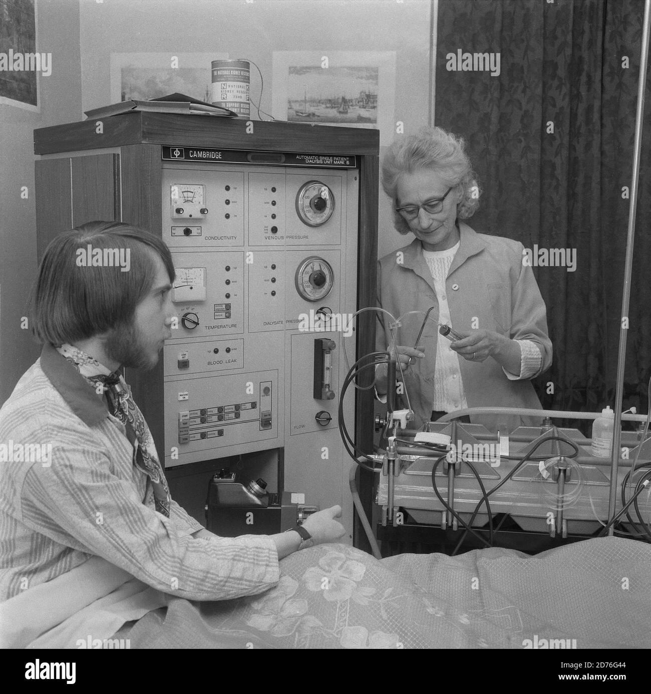 1970s, hospital, a male paient sitting on a hospital bed having dialysis treatment, via a Cambridge Diaysis unit mark 5 machine, adminstered by a female technician at the bedside, Lewisham, Southeast London, England, UK. Such treament is used when vital organs of the body do not function properly. Here the man is having the dialysis for his kidneys which are not performing as they should. The first successful dialysis took place in 1943. Stock Photo