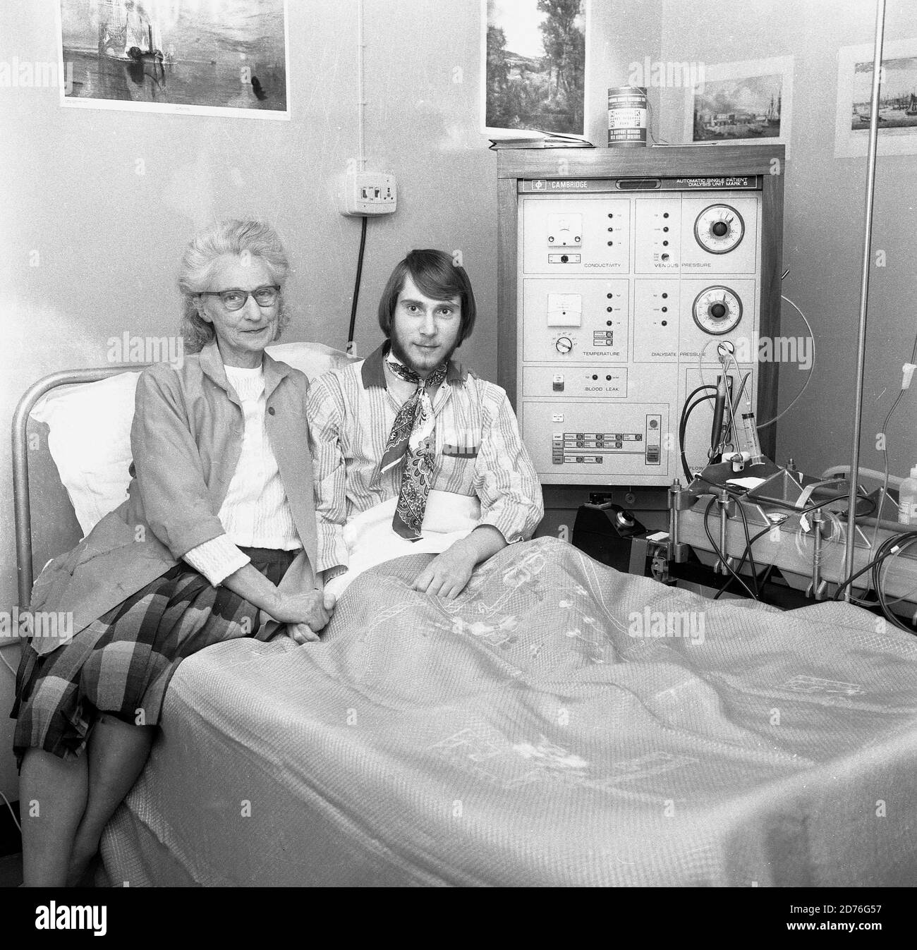 1970s, hospital, a male paient sitting on a hospital bed with his female technician/nurse sitting beside him and holding his hand. He is having dialysis treatment, via a Cambridge Diaysis unit mark 5 machine, Lewisham, Southeast London, England, UK. Such treament is used when vital organs of the body do not function properly. Here the man is having the dialysis for his kidneys which are not performing as they should. The first successful dialysis took place in 1943. Stock Photo
