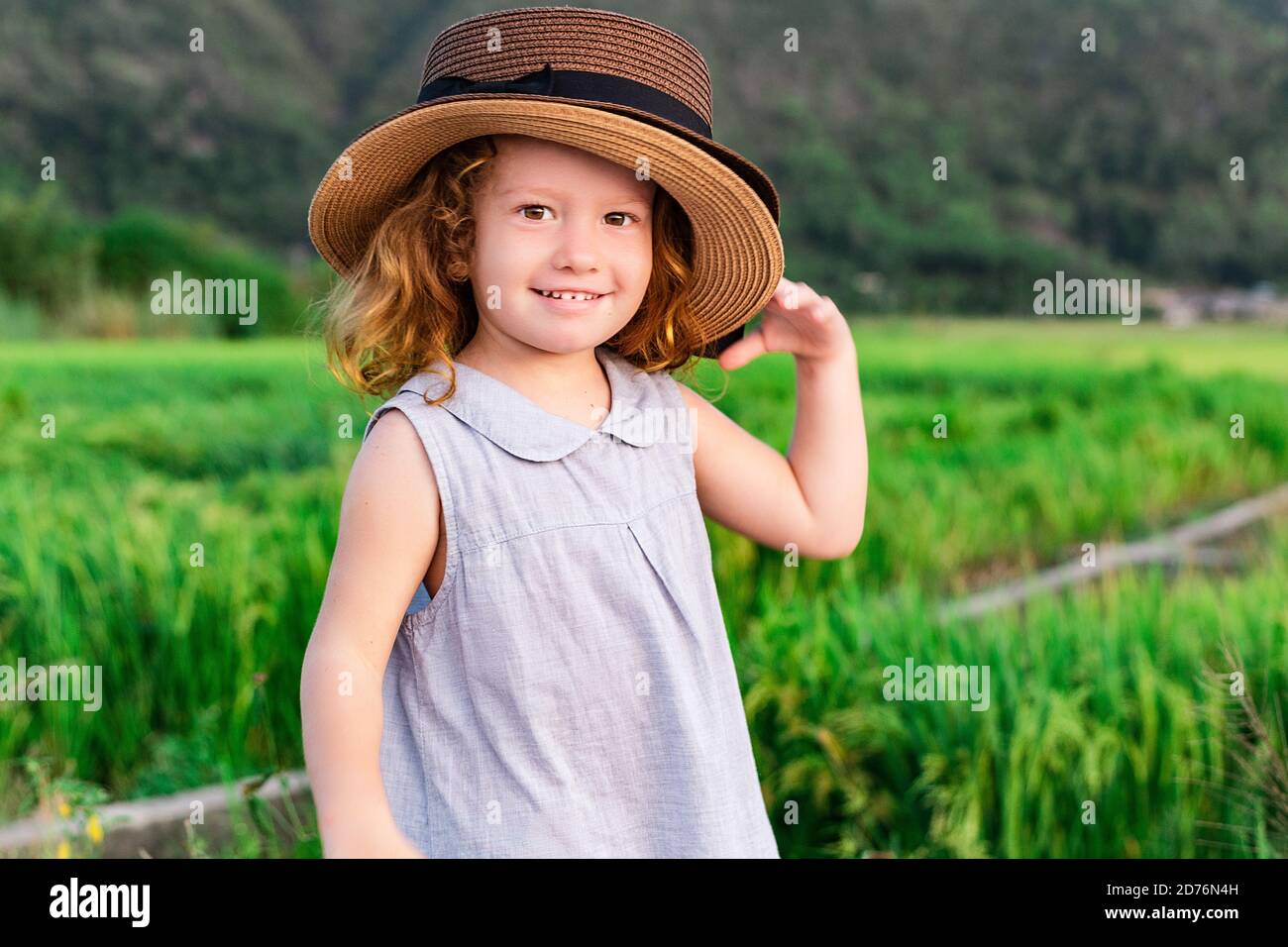 Child girl in straw hat. Cute kid looking at nature lanscape background. Adventure travel concept in retro style Stock Photo